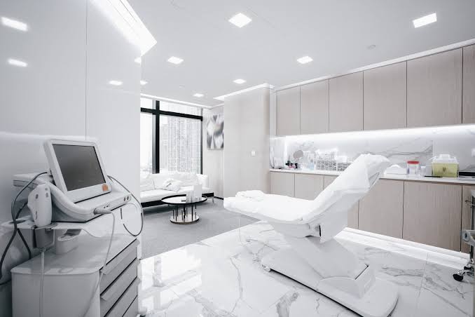 A bright, white clinic treatment room with a treatment chair, marble floor and city windows