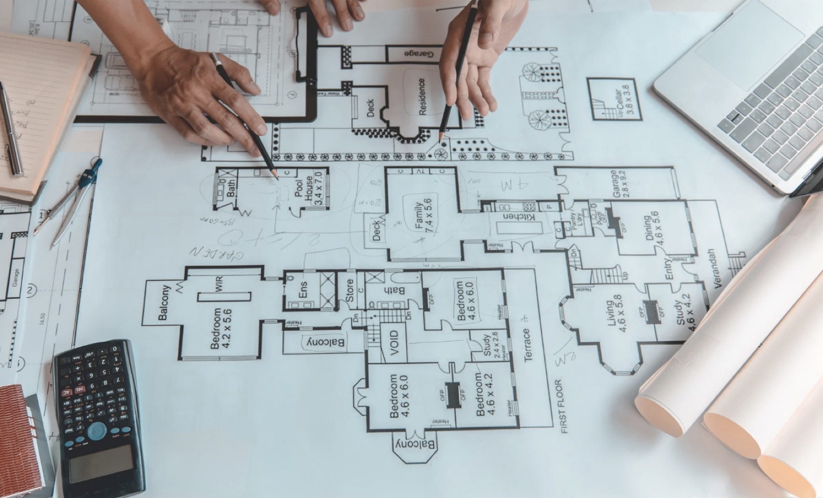Two people marking up a home floor plan with pencils